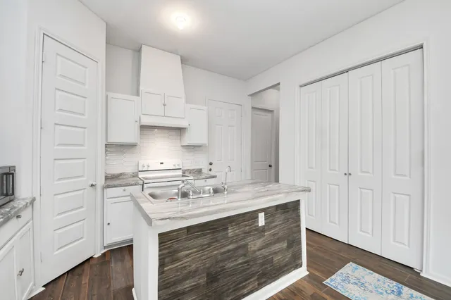 a kitchen with granite countertop a sink a stove and refrigerator