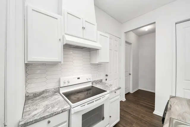 a kitchen with granite countertop a table chairs stove and wooden floor