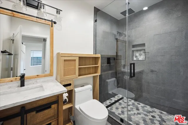 a bathroom with a sink a toilet a mirror and shower
