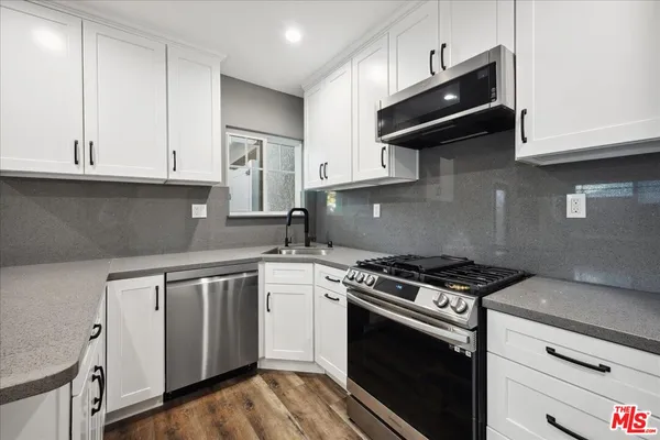 a kitchen with granite countertop cabinets stainless steel appliances and wooden floor