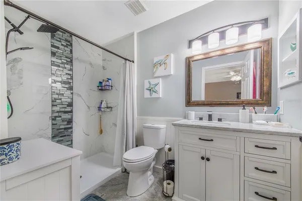 a bathroom with a granite countertop sink toilet a mirror a vanity and shower