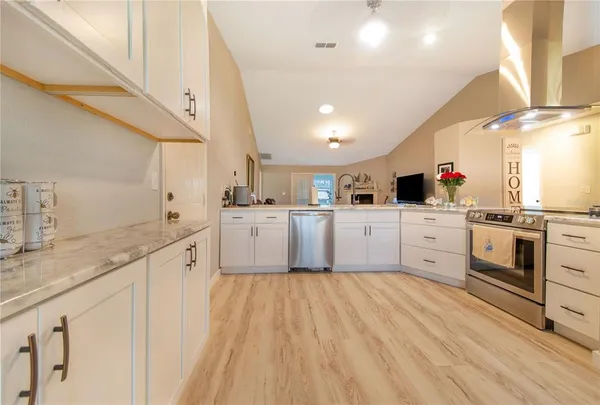 a kitchen with white cabinets appliances and a window