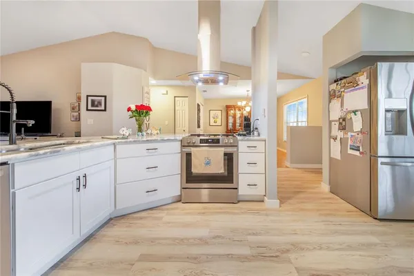 a large white kitchen with a refrigerator a stove a sink dishwasher and white cabinets next to a window