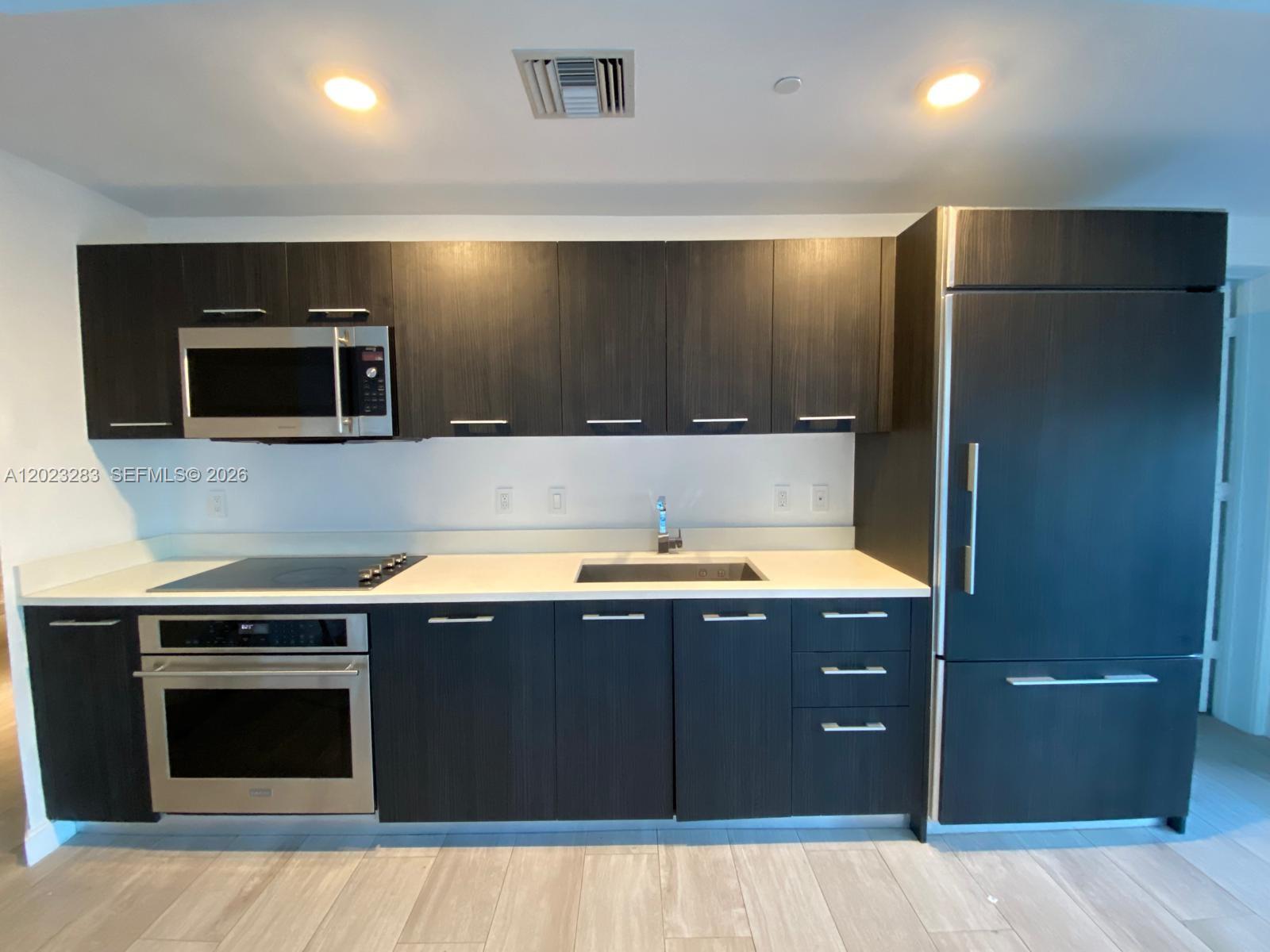55 Southwest 9th Street, Unit 1503 Miami, FL 33130 - Photo 3 of 11 a kitchen with a stove and a microwave