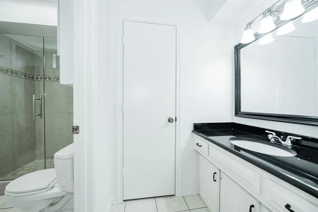a bathroom with a granite countertop sink a toilet a mirror and shower