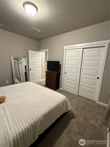 a bedroom with a bed and a flat tv screen on the dresser