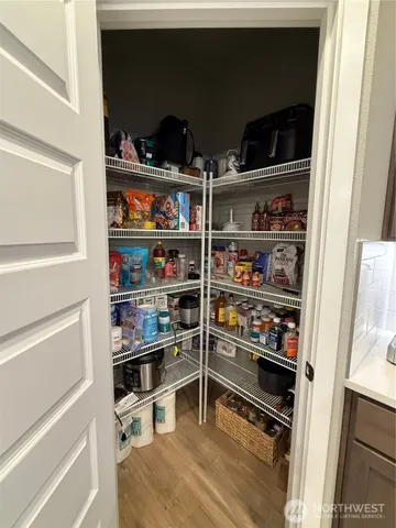 a kitchen with stainless steel appliances a sink a stove a refrigerator white cabinets and wooden floor