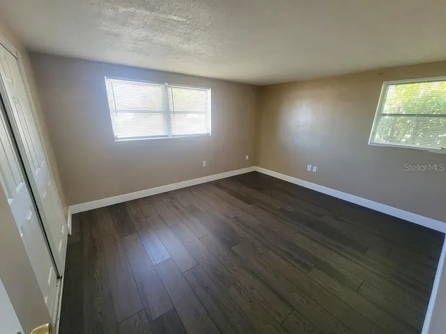 a view of an empty room with wooden floor and a window
