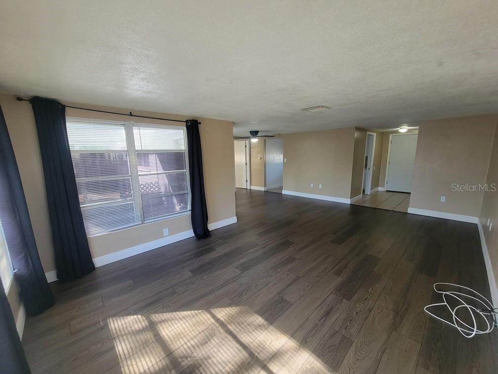 7922 Kelpie Drive Port Richey, FL 34668 - Photo 4 of 24 an empty room with wooden floor and windows