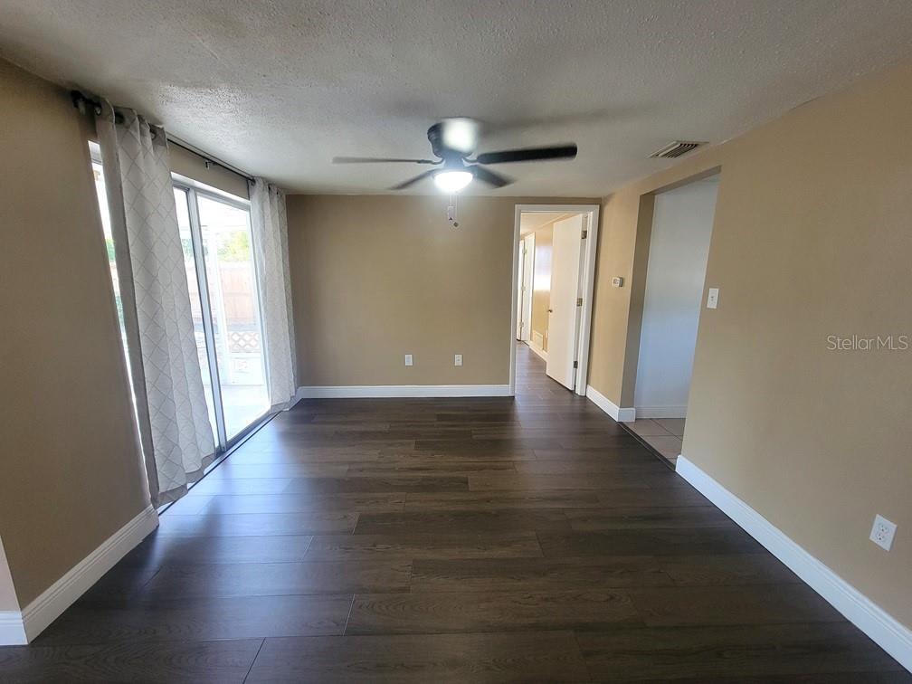 7922 Kelpie Drive Port Richey, FL 34668 - Photo 6 of 24 a view of an empty room with wooden floor and a window