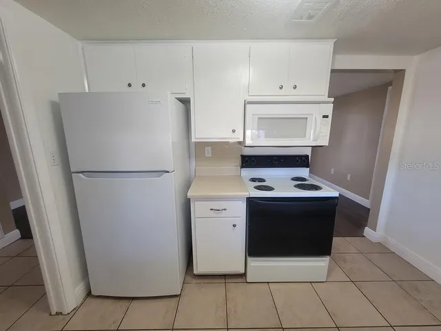a kitchen with a stove top oven and white cabinets