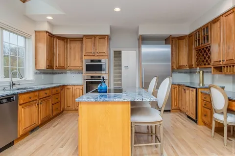 a kitchen with stainless steel appliances granite countertop a kitchen island a stove a sink a dining table and chairs