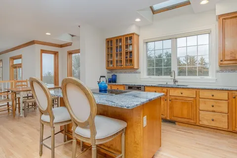 a kitchen with granite countertop wooden cabinets dining table and chairs