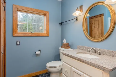 a bathroom with a granite countertop toilet sink and mirror