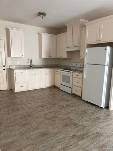 a kitchen with granite countertop white cabinets and white appliances