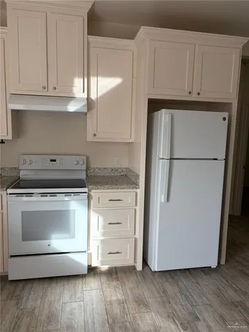 a kitchen with granite countertop white cabinets and white appliances