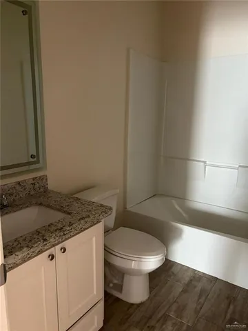 a bathroom with a granite countertop sink a toilet and a bathtub