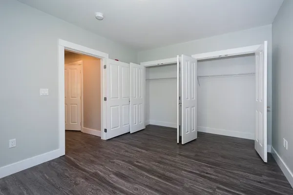 an empty room with wooden floor & closet area