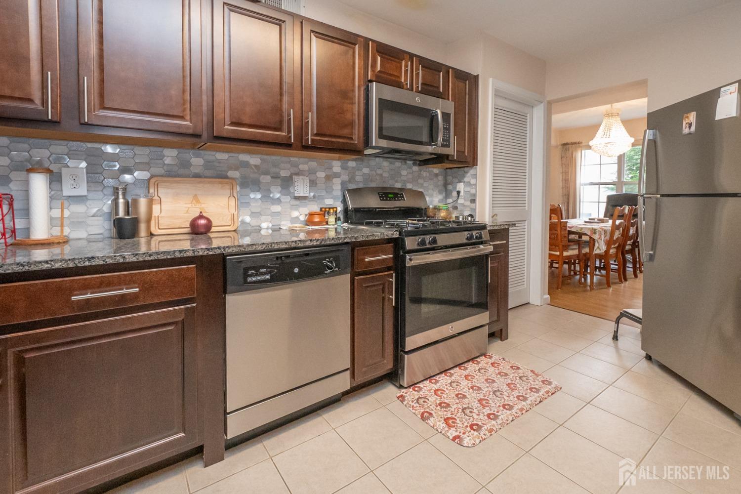 1405 Plymouth Road North Brunswick, NJ 08902 - Photo 11 of 32 a kitchen with stainless steel appliances granite countertop a stove a sink dishwasher and a refrigerator with wooden cabinets