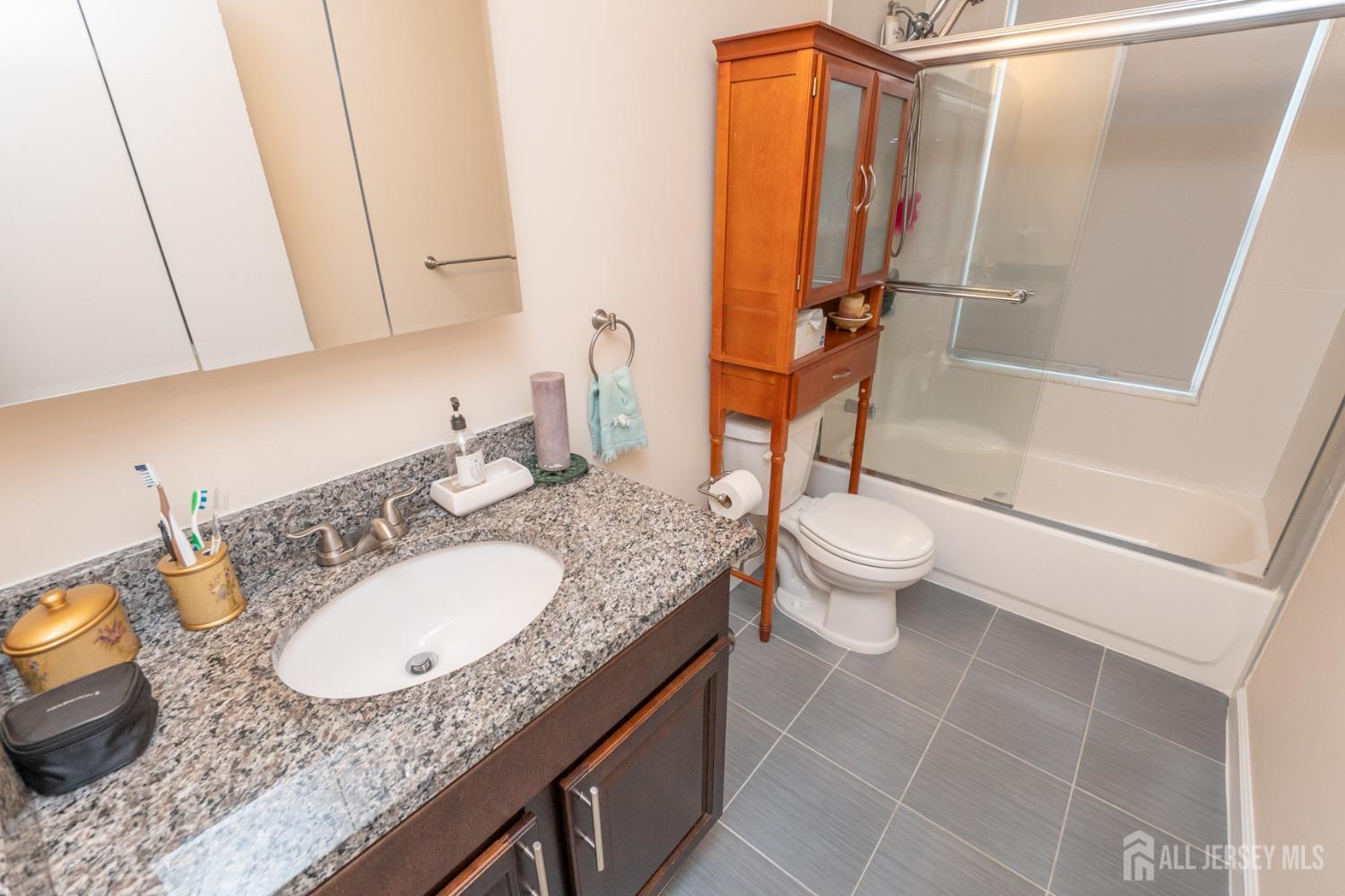 1405 Plymouth Road North Brunswick, NJ 08902 - Photo 24 of 32 a bathroom with a granite countertop sink a toilet and a mirror