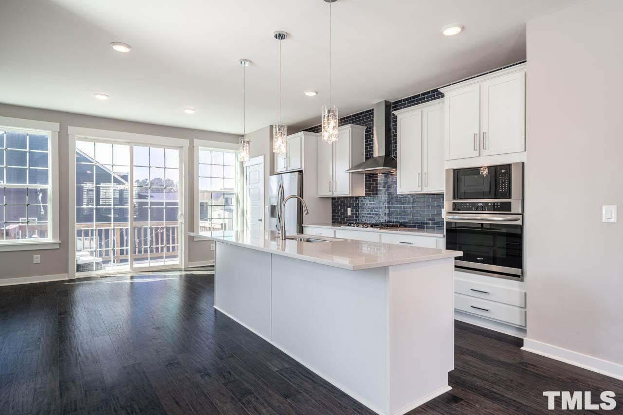 444 Rally Point Place Wake Forest, NC 27587 - Photo 16 of 38 a large kitchen with stainless steel appliances a large counter top a stove a refrigerator cabinets and a wooden floor