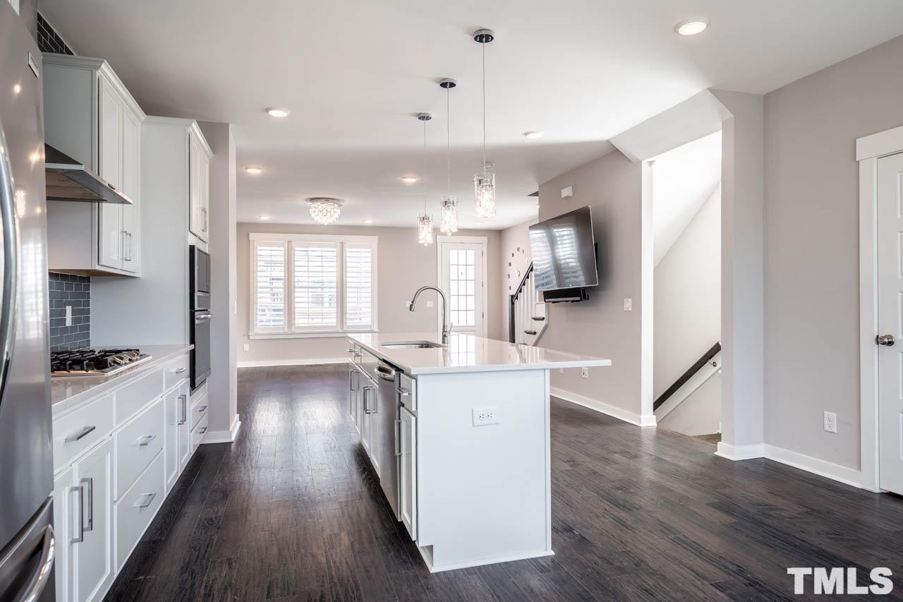 444 Rally Point Place Wake Forest, NC 27587 - Photo 17 of 38 a kitchen with stainless steel appliances kitchen island wooden floors and white cabinets