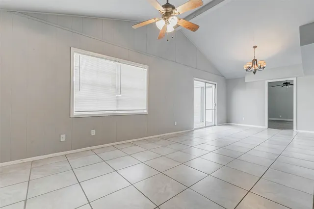 a view of an empty room with window and chandelier fan