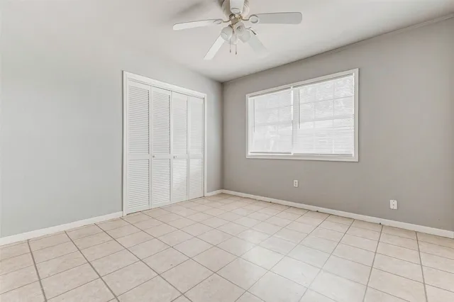 an empty room with chandelier fan and window