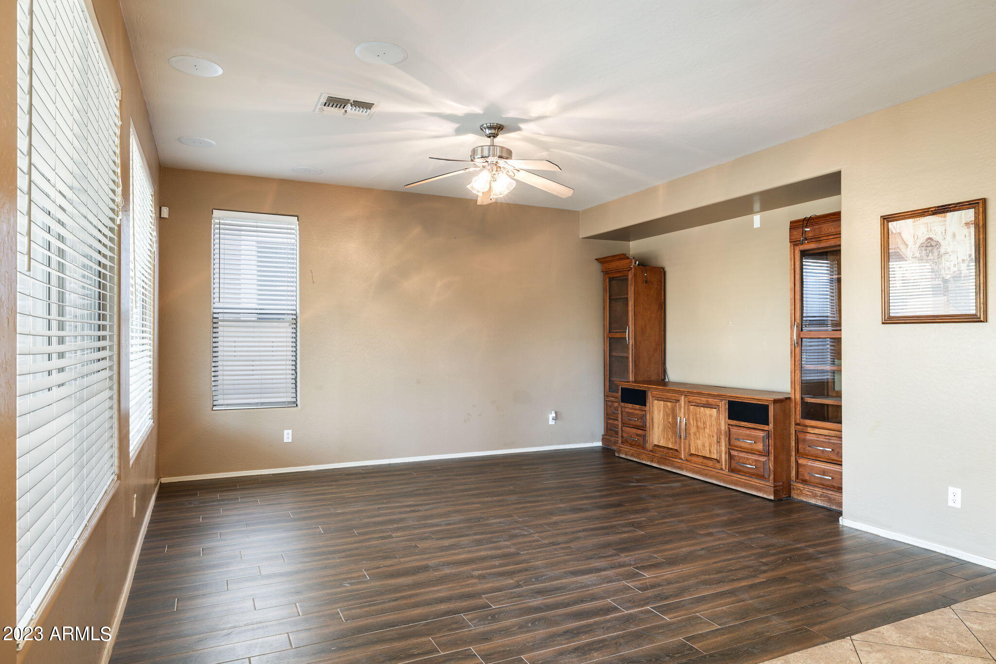 3344 West Montello Road Phoenix, AZ 85086 - Photo 6 of 38 an empty room with wooden floor chandelier fan and windows