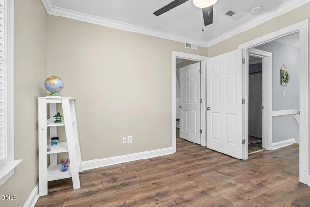 an empty room with wooden floor and ceiling fan
