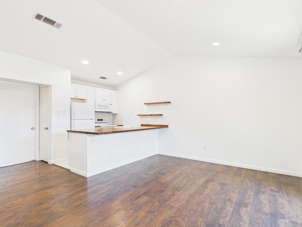 a room with kitchen island a sink cabinets and wooden floor