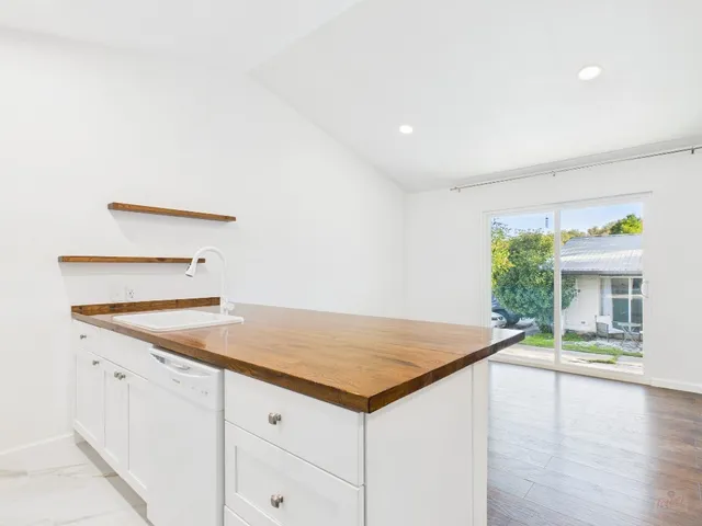 a view of a kitchen that has a sink and a stove with wooden floor