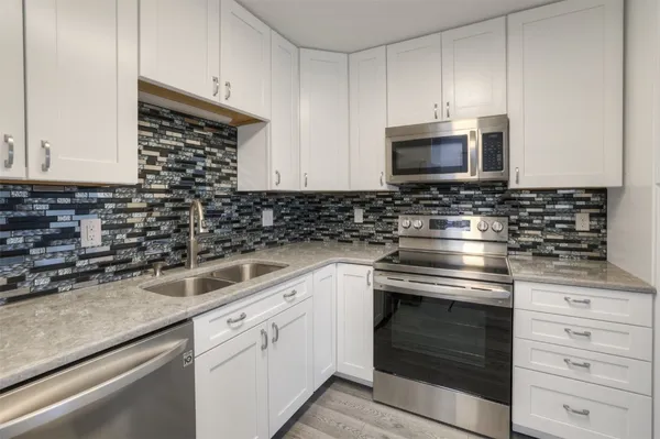 a kitchen with white cabinets and appliances
