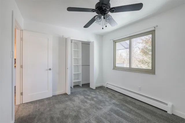an empty room with windows and fan