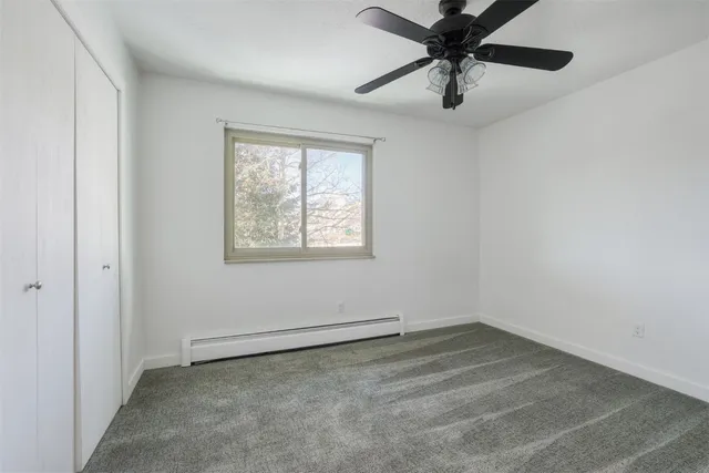an empty room with a window and a fan