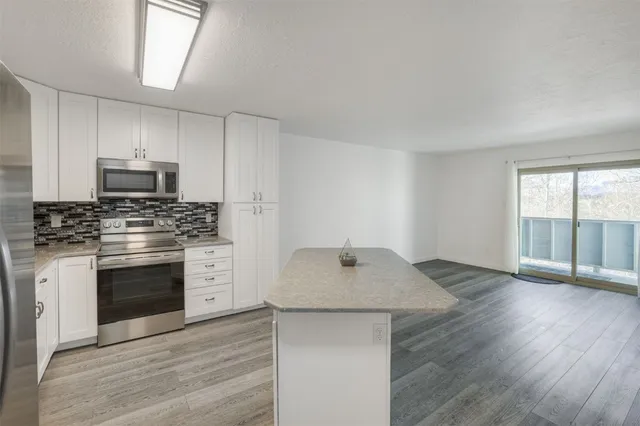 a kitchen with granite countertop a stove a sink and a microwave