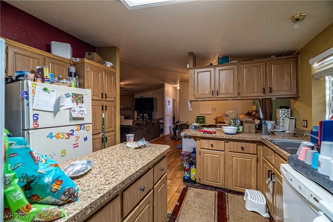 4231 West Wilson Road Pahrump, NV 89048 - Photo 6 of 15 Kitchen featuring light countertops, a sink, wood finished floors, a peninsula, and white appliances