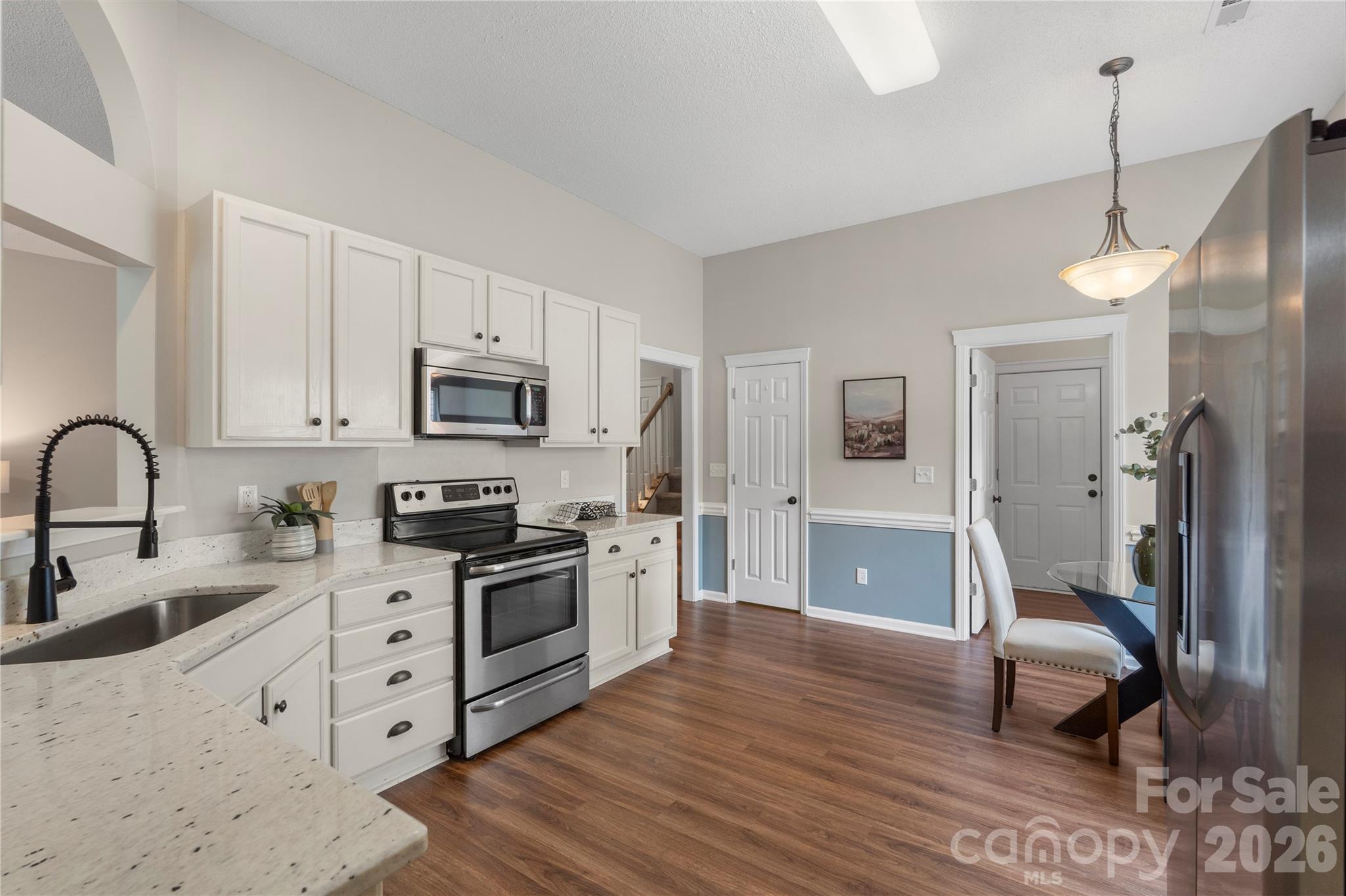 12028 Regent Ridge Lane Charlotte, NC 28278 - Photo 15 of 42 a kitchen with stainless steel appliances granite countertop a stove a sink dishwasher a refrigerator and a dining table with wooden floor