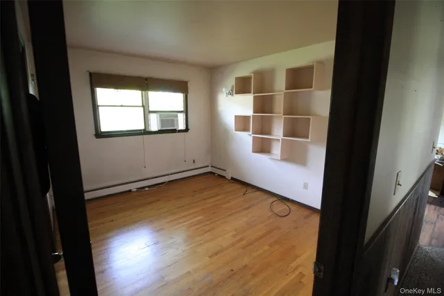 a view of an empty room with wooden floor and a window