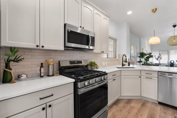 a kitchen with white cabinets and appliances