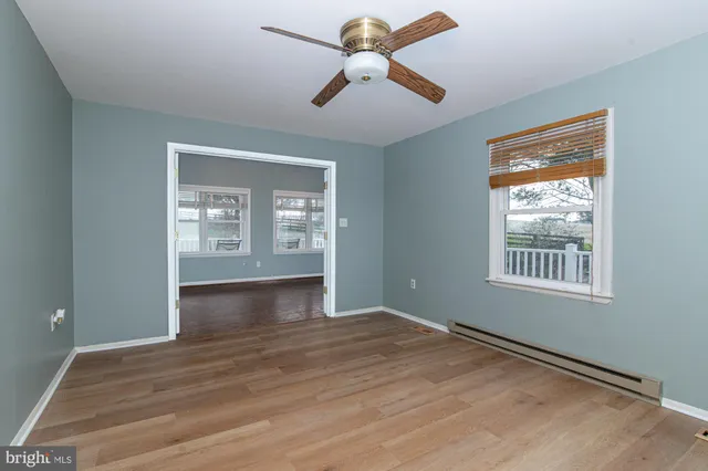 a view of empty room with wooden floor and fan
