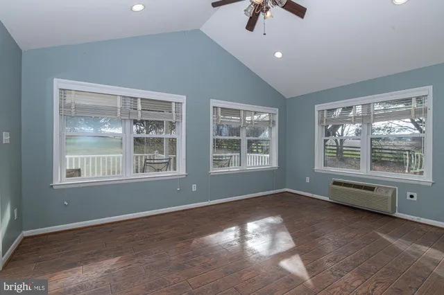 an empty room with chandelier fan and windows