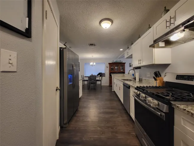 a large kitchen with stainless steel appliances a refrigerator a stove top oven a sink and dishwasher