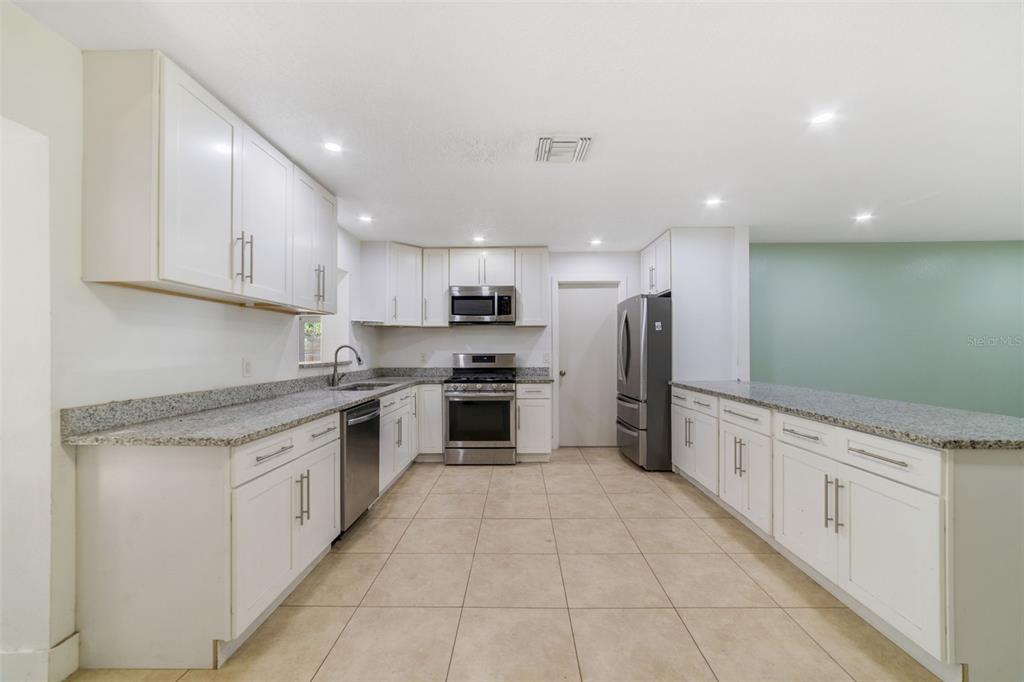 449 Citadel Drive Altamonte Springs, FL 32714 - Photo 4 of 25 a kitchen with granite countertop a refrigerator oven a sink and cabinets
