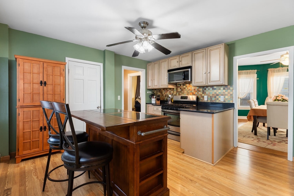 58 Saunders Street North Andover, MA 01845 - Photo 4 of 14 a kitchen with granite countertop a refrigerator a stove a sink a dining table and chairs with wooden floor