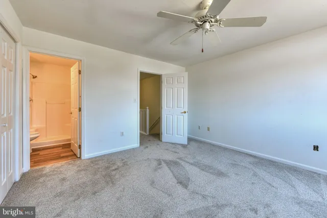 an empty room with closet and a ceiling fan