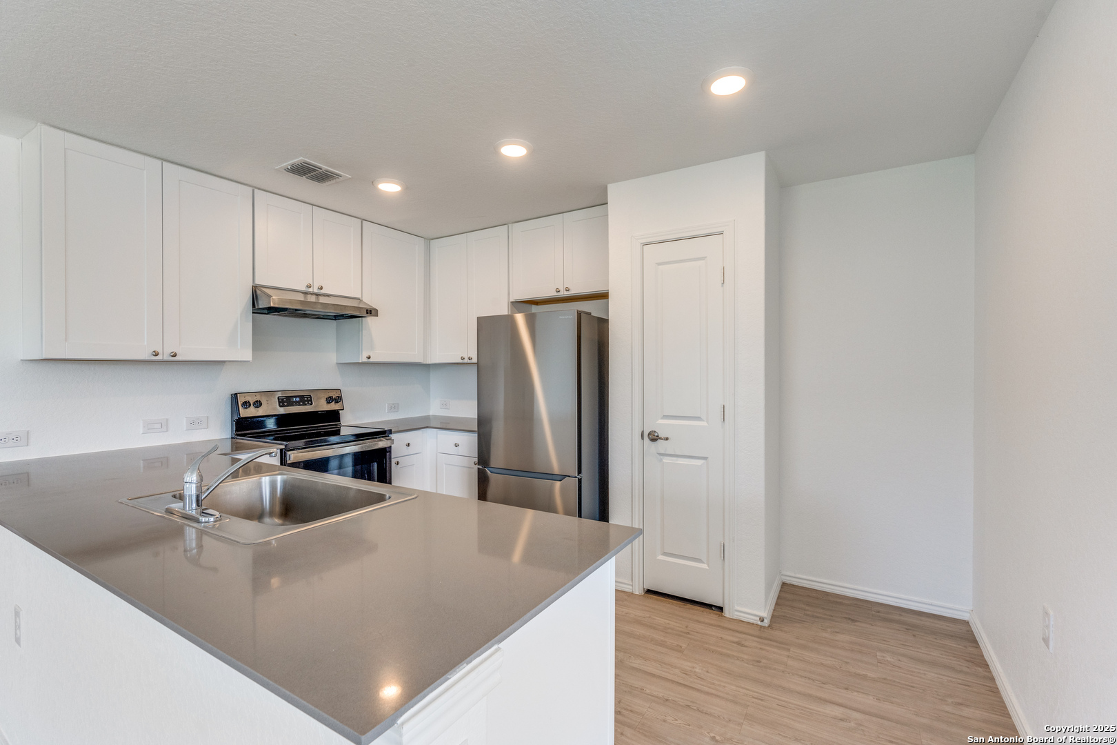 13503 Turnesa Terrace San Antonio, TX 78221 - Photo 5 of 25 a kitchen with stainless steel appliances granite countertop a refrigerator a sink a stove and white cabinets with wooden floor