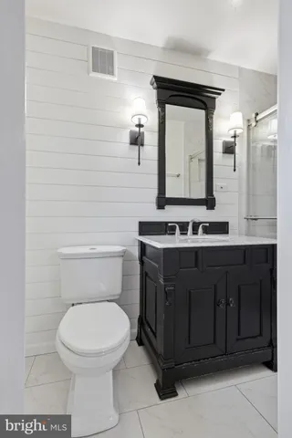 a bathroom with a toilet sink vanity and mirror