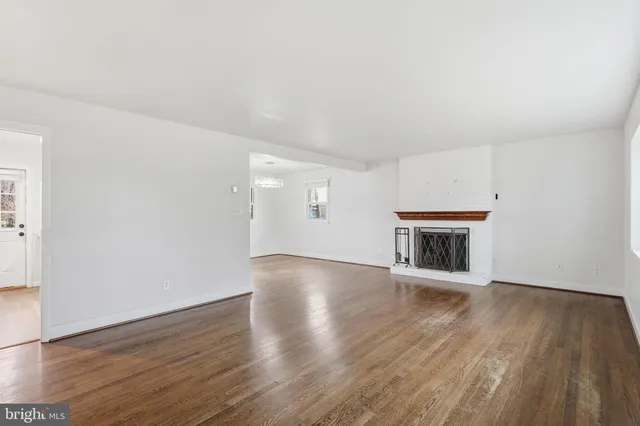 an empty room with wooden floor fireplace and windows