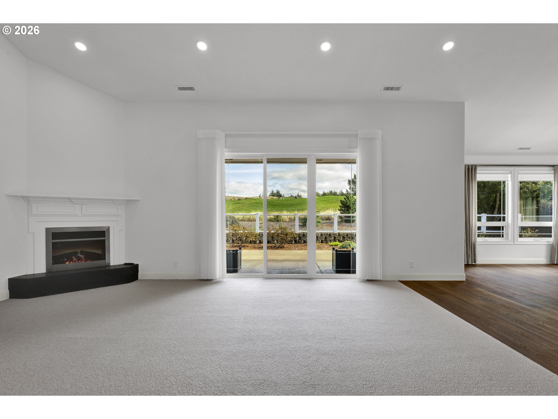 2116 Willow Loop East Florence, OR 97439 - Photo 11 of 47 a view of an empty room with a fireplace and a large window
